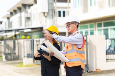 İki Asyalı erkek ve kadın mühendis işi inceliyor. İki kadın mimar, erkek bir mühendis ile birlikte binayı inceliyor..