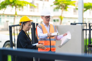 İki Asyalı erkek ve kadın mühendis işi inceliyor. İki kadın mimar, erkek bir mühendis ile birlikte binayı inceliyor..