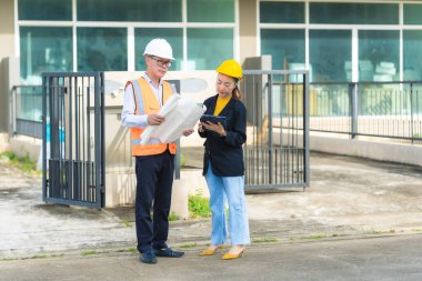 İki Asyalı erkek ve kadın mühendis işi inceliyor. İki kadın mimar, erkek bir mühendis ile birlikte binayı inceliyor..