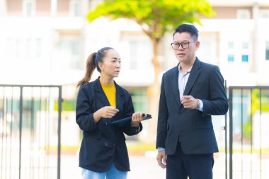 Proje yöneticisi, köy emlak şirketindeki yol yapım çalışmalarının ilerlemesini kontrol etmek için asistanına danışıyor..