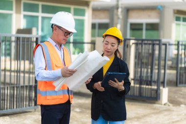 İki Asyalı erkek ve kadın mühendis işi inceliyor. İki kadın mimar, erkek bir mühendis ile birlikte binayı inceliyor..
