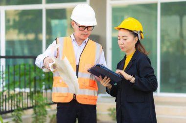 İki Asyalı erkek ve kadın mühendis işi inceliyor. İki kadın mimar, erkek bir mühendis ile birlikte binayı inceliyor..