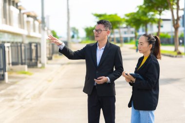 Proje yöneticisi, köy emlak şirketindeki yol yapım çalışmalarının ilerlemesini kontrol etmek için asistanına danışıyor..