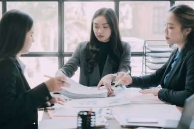 Üç Asyalı iş kadını belge grafiklerinden para kazanıyor, fikirleri analiz ediyor, takım çalışması, belgelerle işbirliği yapıyor ve ofisteki iş stratejileriyle plan yapıyor. iş başlangıç konsepti