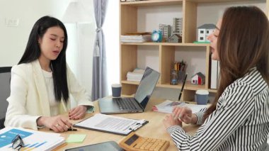 Birlikte çalışan iki Asyalı iş kadını kararlı ve profesyoneldir. Birlikte çalışırlar. Gülümser ve bilgisayarla ve tabletle belgeleri tartışırlar.