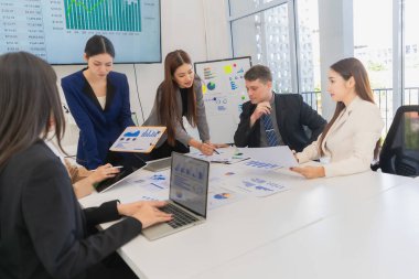 Asyalı iş adamlarından oluşan bir grup, verimli toplantı sırasında çizelge ve grafikleri analiz ediyor, takım çalışması ve işbirliği, finansal iş konsepti gösteriyorlar..