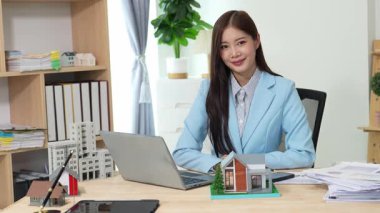 Asyalı bayan emlakçı müşterilere internet üzerinden danışmanlık hizmeti sunar müşteriye bir ev ya da dairenin içini tarif eder. Çevrimiçi ev satışı danışmanı