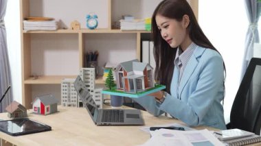 Asyalı bayan emlakçı müşterilere internet üzerinden danışmanlık hizmeti sunar müşteriye bir ev ya da dairenin içini tarif eder. Çevrimiçi ev satışı danışmanı