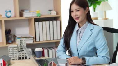 Bilgisayarı ve finansal belgeleri olan genç Asyalı kadın çalışanlar ofis masasında gülümsüyor ve grafikleri gösteren bilgisayarlarla çalışıyor. başlangıç iş fikri