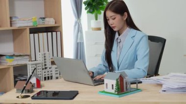 Asyalı bayan emlakçı müşterilere internet üzerinden danışmanlık hizmeti sunar müşteriye bir ev ya da dairenin içini tarif eder. Çevrimiçi ev satışı danışmanı