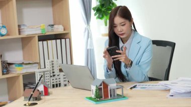 Asyalı bayan emlakçı müşterilere internet üzerinden danışmanlık hizmeti sunar müşteriye bir ev ya da dairenin içini tarif eder. Çevrimiçi ev satışı danışmanı