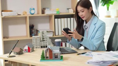 Asyalı bayan emlakçı müşterilere internet üzerinden danışmanlık hizmeti sunar müşteriye bir ev ya da dairenin içini tarif eder. Çevrimiçi ev satışı danışmanı