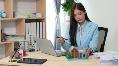 Asyalı bayan emlakçı müşterilere internet üzerinden danışmanlık hizmeti sunar müşteriye bir ev ya da dairenin içini tarif eder. Çevrimiçi ev satışı danışmanı