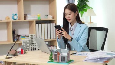 Asyalı bayan emlakçı müşterilere internet üzerinden danışmanlık hizmeti sunar müşteriye bir ev ya da dairenin içini tarif eder. Çevrimiçi ev satışı danışmanı