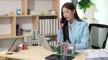 Asyalı bayan emlakçı müşterilere internet üzerinden danışmanlık hizmeti sunar müşteriye bir ev ya da dairenin içini tarif eder. Çevrimiçi ev satışı danışmanı