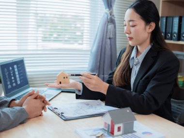 Asyalı kadın ev satış temsilcisi, kiracılarla ev satın alma sözleşmesi imzaladıktan sonra müşterilerine tavsiyede bulunuyor. Ev sahibi müşterilere gayrimenkul satıyor. Yatırım için mutlu çift.