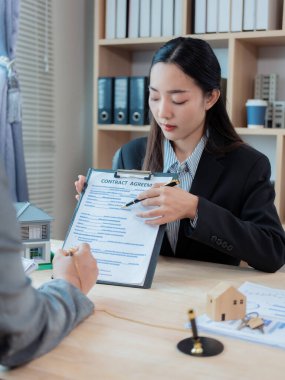 Asyalı kadın ev satış temsilcisi, kiracılarla ev satın alma sözleşmesi imzaladıktan sonra müşterilerine tavsiyede bulunuyor. Ev sahibi müşterilere gayrimenkul satıyor. Yatırım için mutlu çift.
