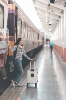 Tren istasyonunda valizli genç Asyalı kadın gezgin, tren istasyonunda yürüyen kadın.