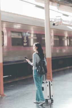 Tren istasyonunda valizli genç Asyalı kadın gezgin, tren istasyonunda yürüyen kadın.