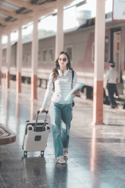 Tren istasyonunda valizli genç Asyalı kadın gezgin, tren istasyonunda yürüyen kadın.