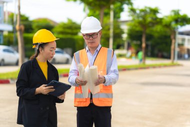 İnşaat alanında planları olan kadın mimar veya mühendis, takım çalışması tartışması, Kafkas kadın inşaat mühendisi yatırımcılarla konut projesinin ilerlemesini kontrol ediyor.