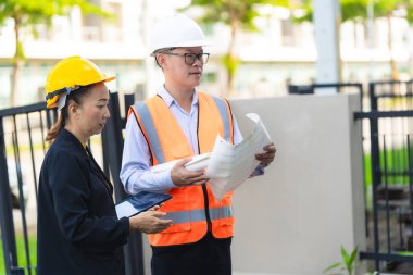 İnşaat alanında planları olan kadın mimar veya mühendis, takım çalışması tartışması, Kafkas kadın inşaat mühendisi yatırımcılarla konut projesinin ilerlemesini kontrol ediyor.
