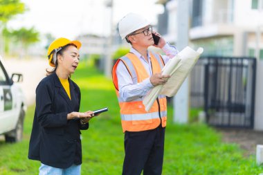 İnşaat alanında planları olan kadın mimar veya mühendis, takım çalışması tartışması, Kafkas kadın inşaat mühendisi yatırımcılarla konut projesinin ilerlemesini kontrol ediyor.