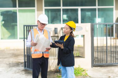 İnşaat alanında planları olan kadın mimar veya mühendis, takım çalışması tartışması, Kafkas kadın inşaat mühendisi yatırımcılarla konut projesinin ilerlemesini kontrol ediyor.