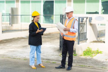 İnşaat alanında planları olan kadın mimar veya mühendis, takım çalışması tartışması, Kafkas kadın inşaat mühendisi yatırımcılarla konut projesinin ilerlemesini kontrol ediyor.