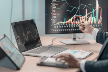 İşadamı, finansal tablet ve dizüstü bilgisayarla finansal tabletleri analiz ederek bilgisayardaki büyüme grafiklerini analiz ediyor. Yakın vadeli borsa büyümesine yönelik yatırım stratejileri