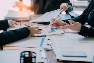 Takımlar proje stratejisi üzerinde çalışır, raporları hazırlar, konferans masasındaki bilgi grafiklerine işaret ederler. Satış sonuçlarını analiz et piyasa araştırması yap, yakın plan resimler çek