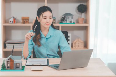 Ev satışı, Asyalı kadınlarla online istişare ahşap ev modeli, anahtar ve dokümanlar ile emlak konsepti.