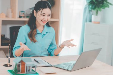 Ev satışı, Asyalı kadınlarla online istişare ahşap ev modeli, anahtar ve dokümanlar ile emlak konsepti.