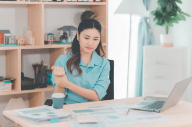 Ofis sendromundan muzdarip güzel Asyalı iş kadınının dizüstü bilgisayarla uzun süre çalıştıktan sonra boynunda, omuzlarında ve kollarında ağrı var..