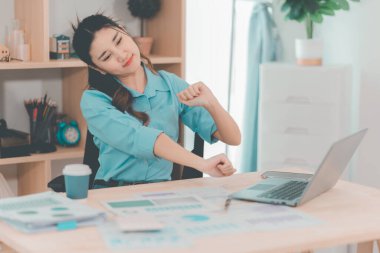 Ofis sendromundan muzdarip güzel Asyalı iş kadınının dizüstü bilgisayarla uzun süre çalıştıktan sonra boynunda, omuzlarında ve kollarında ağrı var..