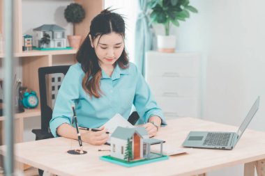 Ev satışı, Asyalı kadınlarla online istişare ahşap ev modeli, anahtar ve dokümanlar ile emlak konsepti.