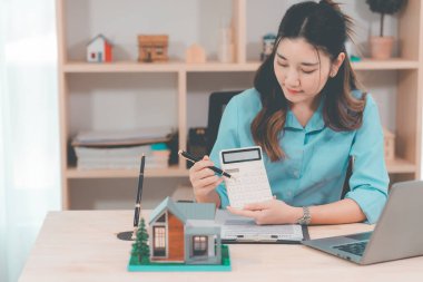 Ev satışı, Asyalı kadınlarla online istişare ahşap ev modeli, anahtar ve dokümanlar ile emlak konsepti.