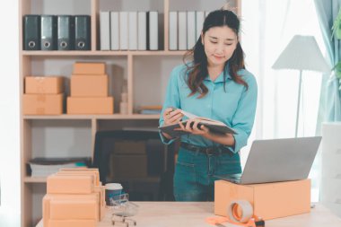 Küçük bir iş girişimiydi. KOBİ sahibi. Kadın girişimci çevrimiçi siparişleri kontrol ediyor. Kutuları teslimat için hazırlayıp müşterilere satmak için. Çevrimiçi KOBİ iş fikri.
