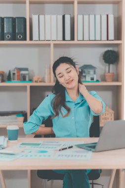 Ofis sendromundan muzdarip güzel Asyalı iş kadınının dizüstü bilgisayarla uzun süre çalıştıktan sonra boynunda, omuzlarında ve kollarında ağrı var..