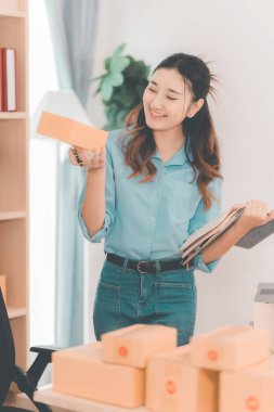 Küçük bir iş girişimiydi. KOBİ sahibi. Kadın girişimci çevrimiçi siparişleri kontrol ediyor. Kutuları teslimat için hazırlayıp müşterilere satmak için. Çevrimiçi KOBİ iş fikri.