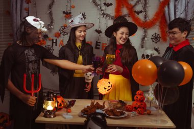 Asian man and woman celebrating Halloween, pumpkins at night, Halloween banner background for holiday activities.