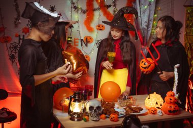 Asian man and woman celebrating Halloween, pumpkins at night, Halloween banner background for holiday activities.