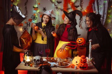 Asian man and woman celebrating Halloween, pumpkins at night, Halloween banner background for holiday activities.