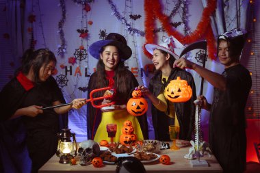 Asian man and woman celebrating Halloween, pumpkins at night, Halloween banner background for holiday activities.