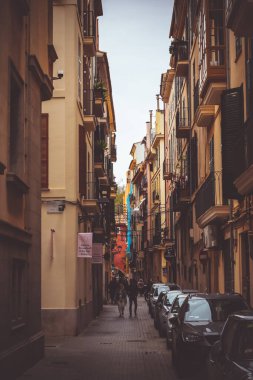 Palma de Mallorca, İspanya, 4 Nisan 2022 - İnsanlı ve durgun arabalı sinematik dar cadde