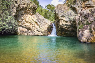 Doğanın huzur dolu güzelliğini, küçük bir şelalenin kristal bir havuza dökülüşünün bu çarpıcı fotoğrafıyla yaşayın. Görüntü kayaların üzerinde yuvarlanan suyun yumuşak akışını yakalıyor, dingin ve rahatlatıcı bir ortam yaratıyor.. 