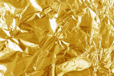 Altın folyo yaprağının parlak dokusu, arkaplan ve tasarım çalışmaları için soyut sarı ambalaj kağıdı.