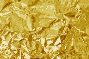 Altın folyo yaprağının parlak dokusu, arkaplan ve tasarım çalışmaları için soyut sarı ambalaj kağıdı.