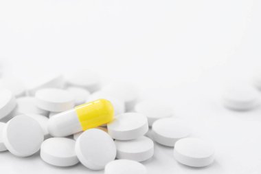 Sarı ve beyaz ilaç hapları, kapsüller, tabletler beyaz bir masada. Önden bak ve uzayı kopyala. Tıp ve sağlık hizmetleri kavramı.