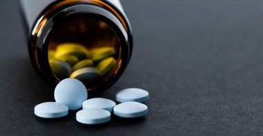 İlaç şişesi mavi hapları döküyor, kopyalama alanı, metin için boşluk.